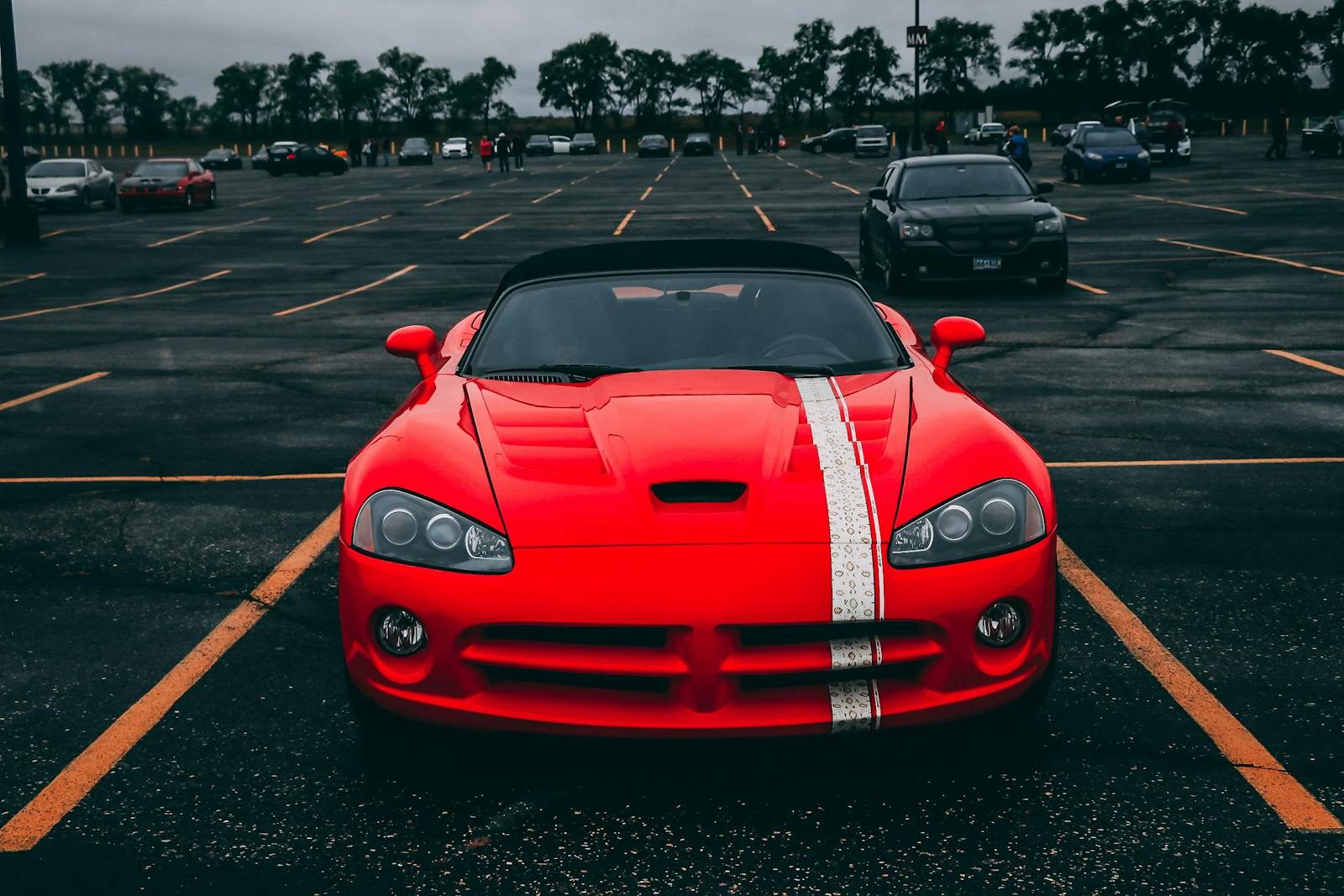 Vibrant red sports car parked in an empty lot with overcast skies.